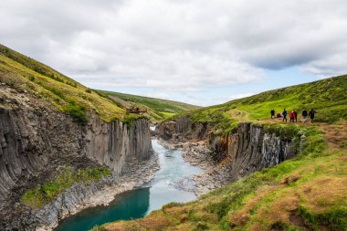 Studlagil İzlanda - 16 Temmuz. 2021: Studlagil Kanyonu 'nun nefes kesici manzarasının tadını çıkaran turistler