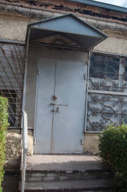 Entrance gray metal door in the wall of the old workshop of the enterprise