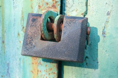 A padlock hangs on old metal garage or warehouse doors.