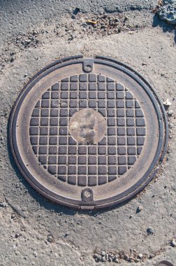 one metal sewer hatch lies on the road in the street