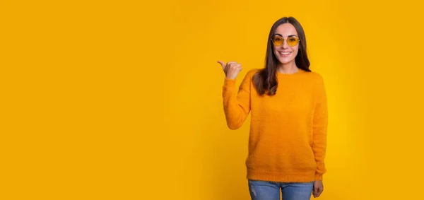 Cute Smiling Woman Yellow Sweater Sunglasses Pointing Away While She — Zdjęcie stockowe