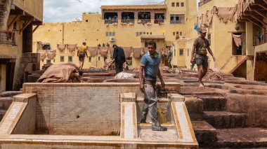 Fez, Fas - Nisan 2018: Chouara Tannery 'deki boya kaplarında çalışan tabakçılar hayvan derileri boyuyor. Yuvarlak taş kuyuları boyayla ya da derileri yumuşatmak için beyaz sıvılarla dolu..
