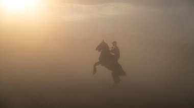 Kayseri, Türkiye - Kasım 2019: Kimliği belirsiz bir adam toz ve sis içinde ata biniyor