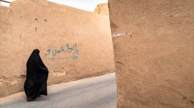 Yazd, İran - Mayıs 2019: Eski Yazd kentinin dar sokaklarında siyah tesettüre bürünmüş, kimliği belirsiz Müslüman kadın
