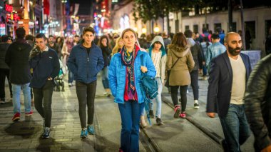 İstanbul, Türkiye - Kasım 2019: İstanbul şehir hayatı, Taksim Meydanı istiklal Caddesi 'nde kalabalık arasında tek başına yürüyen kadın. Fotoğraf hareketi bulanık ve bilerek ve orjinal olarak odak dışı