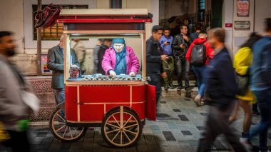 İstanbul, Türkiye - Kasım 2019: Akşam saatlerinde Taksim İstiklal Caddesi 'nde kavrulmuş kestane satan adam. Alan derinliği ve bulanıklaştırma kasıtlı ve orijinal olarak yapılır