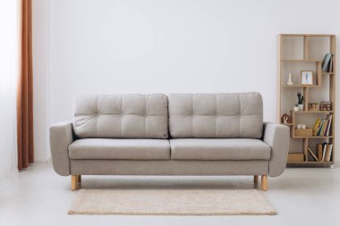 Beyaz minimalist oturma odası, ahşap bir zeminde kanepe, büyük bir duvarda dekor, penceresinde beyaz manzara. Ev Kuzey iç mimarisi.
