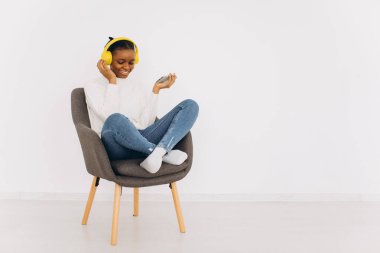 Afro-Amerikalı kadın evde kulaklıkla müzik dinlemekten hoşlanıyor. Boşluğu Kopyala.