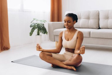 Genç siyahi kadın evde meditasyon yapıyor, yoga konsepti, boş alan.