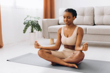 Genç siyahi kadın evde meditasyon yapıyor, yoga konsepti, boş alan.