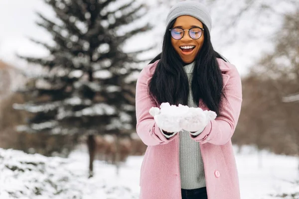 若いアフリカ系アメリカ人女性の眼鏡や暖かい手袋雪の中で遊んで 屋外の公園で時間を過ごす — ストック写真