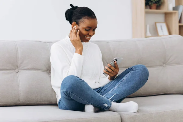 Sonriente Mensajería Chica Negra Teléfono Inteligente Casa Relajarse Sofá Cómodo — Foto de Stock