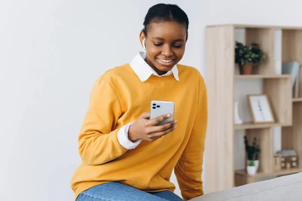 Gülümseyen Siyah Kız Evde Akıllı Telefondan Mesajlaşıyor Rahat Koltukta Dinleniyor — Stok fotoğraf