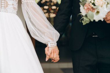 Düğün günü. Damat gelinin elini bokeh arka planda tutar..