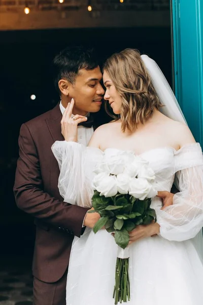 Düğün günü. Güzel Avrupalı gelin ve Asyalı damadı kafelerin ve büyük pencerelerin önünde poz veriyorlar..