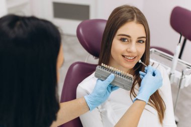Bir kadın diş hekimi hastasına implant ya da kaplamanın rengini renk ölçeği kullanarak seçmesinde yardımcı olur.