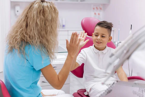 男の子は笑い 歯科での訪問と検査の後 女性歯科医に敬意を表します — ストック写真