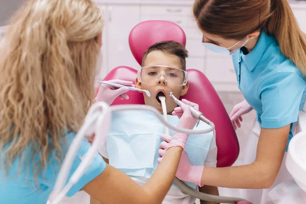女性歯科医は歯科クリニックで男の子の歯を治療します — ストック写真