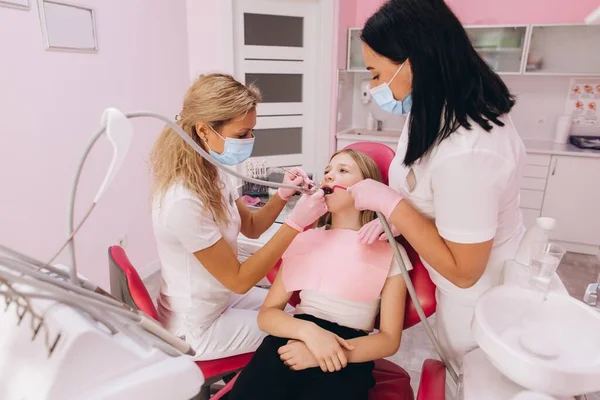 歯医者と助手が十代の女の子の歯を調べる — ストック写真