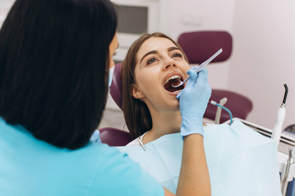 Female dentist examines her patient in a dental chair.