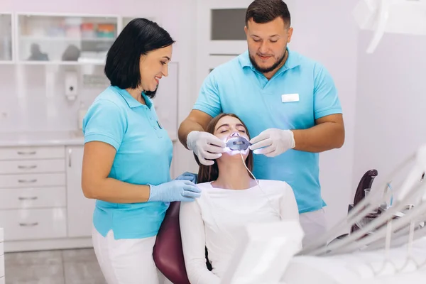 Dentyści Dają Dziewczynie Wybielanie Zębów Klinice Stomatologicznej — Zdjęcie stockowe