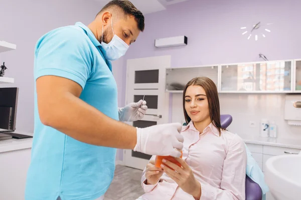 Dentysta Uśmiecha Się Pokazuje Dziewczynie Modelkę Zębami Opowiada Implantacji Próchnicy — Zdjęcie stockowe