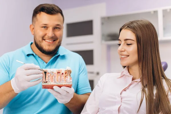 Dentysta Uśmiecha Się Pokazuje Dziewczynie Modelkę Zębami Opowiada Implantacji Próchnicy — Zdjęcie stockowe