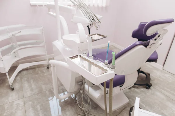 Modern dental practice. Dental chair and other accessories used by dentists in violet, copper light