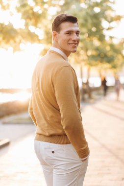 Günbatımında parkta poz veren sarı ve beyaz elbiseli modern yakışıklı adam.