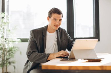 Modern gülümseyen adam, bilgisayarın ofisinde çalışan ofis çalışanı.