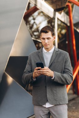 Modern yakışıklı gülümseyen adam sokakta yürüyor ve telefonla konuşuyor.