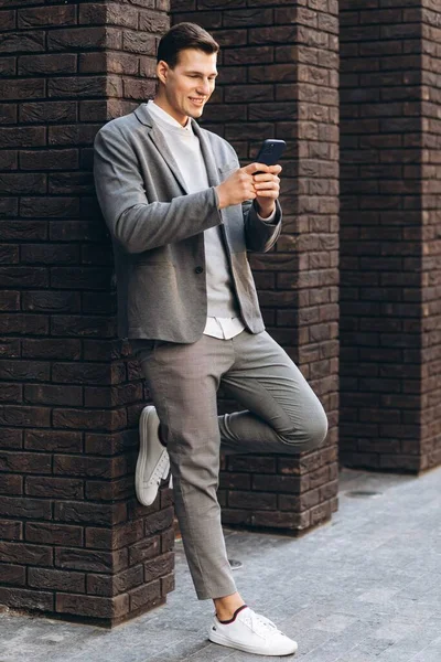 Modern Stilig Leende Man Står Vid Väggen Gatan Håller Telefon — Stockfoto