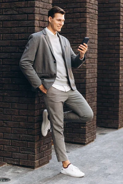 Modern Yakışıklı Gülümseyen Bir Adam Elinde Telefon Olan Bir Duvarın — Stok fotoğraf