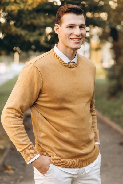 Günbatımında parkta poz veren sarı ve beyaz elbiseli modern yakışıklı adam.