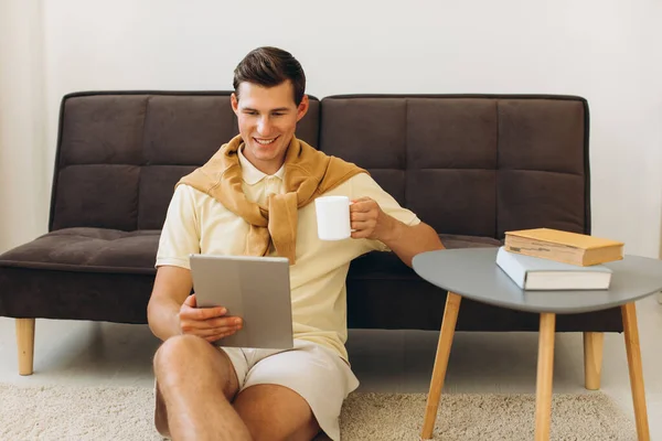 Bonito Jovem Roupas Casuais Amarelas Sentado Casa Lendo Livros Bebendo — Fotografia de Stock