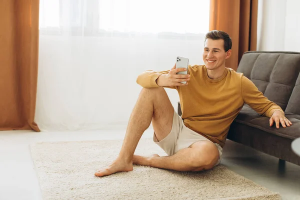 Sarı Giysili Yakışıklı Genç Adam Evde Oturmuş Telefonda Bir Mesaj — Stok fotoğraf