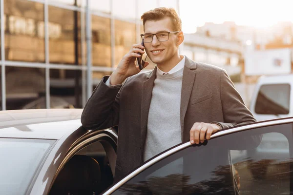 Gözlüklü Yakışıklı Genç Adam Telefonla Konuşuyor Dışarıda Dikilirken Arabasına Biniyor — Stok fotoğraf