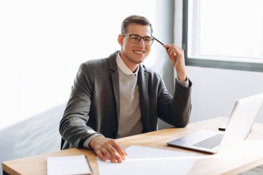 Modern gülümseyen adam, dizüstü bilgisayarda çalışan ofis çalışanı.