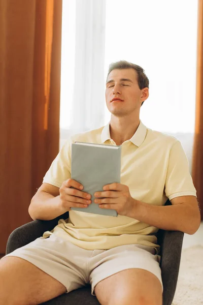 Chico Guapo Está Sentado Una Silla Casa Sosteniendo Una Biblia — Foto de Stock