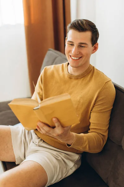 Bonito Jovem Roupas Casuais Amarelas Sentado Casa Lendo Livro — Fotografia de Stock