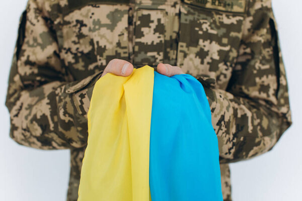 Ukrainian patriot soldier in military uniform holding a yellow and blue flag on a white background