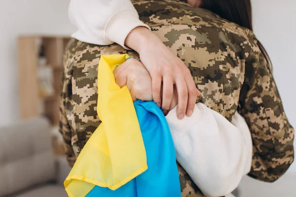 Ukraynalı bir kız üniformalı bir askerin sarı ve mavi bayrağını tutuyor ve ona veda ediyor..