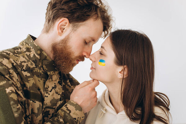 Ukrainian couple, military bearded man in uniform kisses his girlfriend at home