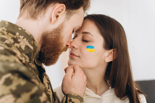 Ukrainian couple, military bearded man in uniform kisses his girlfriend at home