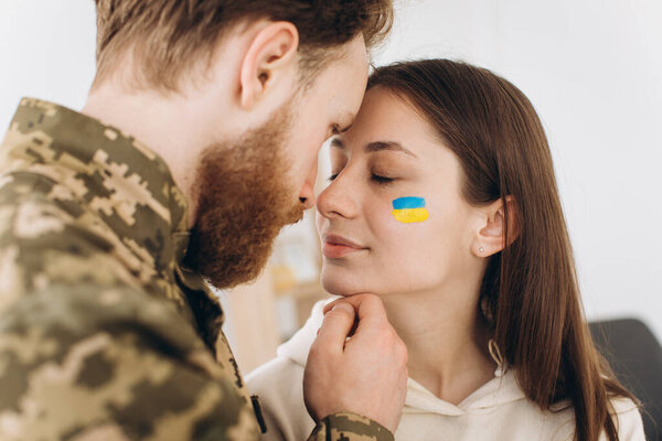Ukrainian couple, military bearded man in uniform kisses his girlfriend at home