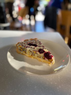 Ahudududulu beyaz çikolatalı tart dilimi ve Pistachio Cafe Shop Restaurant 'ta Plate ile servis ediliyor. Yemeye hazır..