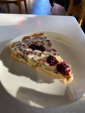 Ahudududulu beyaz çikolatalı tart dilimi ve Pistachio Cafe Shop Restaurant 'ta Plate ile servis ediliyor. Yemeye hazır..