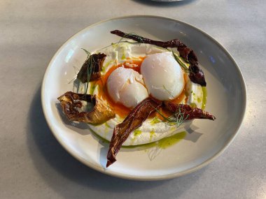 Beyaz kasede Türk yumurtaları. Türk mutfağı konsepti. Yoğurtlu haşlanmış yumurta ve baharatlı tereyağı sosu, yakın plan. Geleneksel yemek.