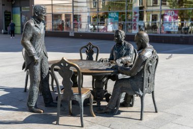 Lodz, Polonya - 9 Eylül 2021: Lodz 'un tarihi şehir merkezinde bir masada oturan bir grup insanın heykel çalışması