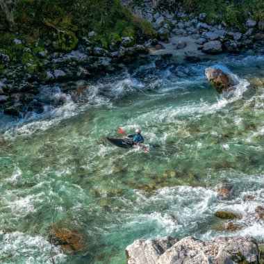 Kobarid, Slovenya - 17 Ekim 2021: Slovenya 'nın kuzeyindeki dağlardaki Soca Nehri' nin berrak turkuaz sularında yüzen kanocu.